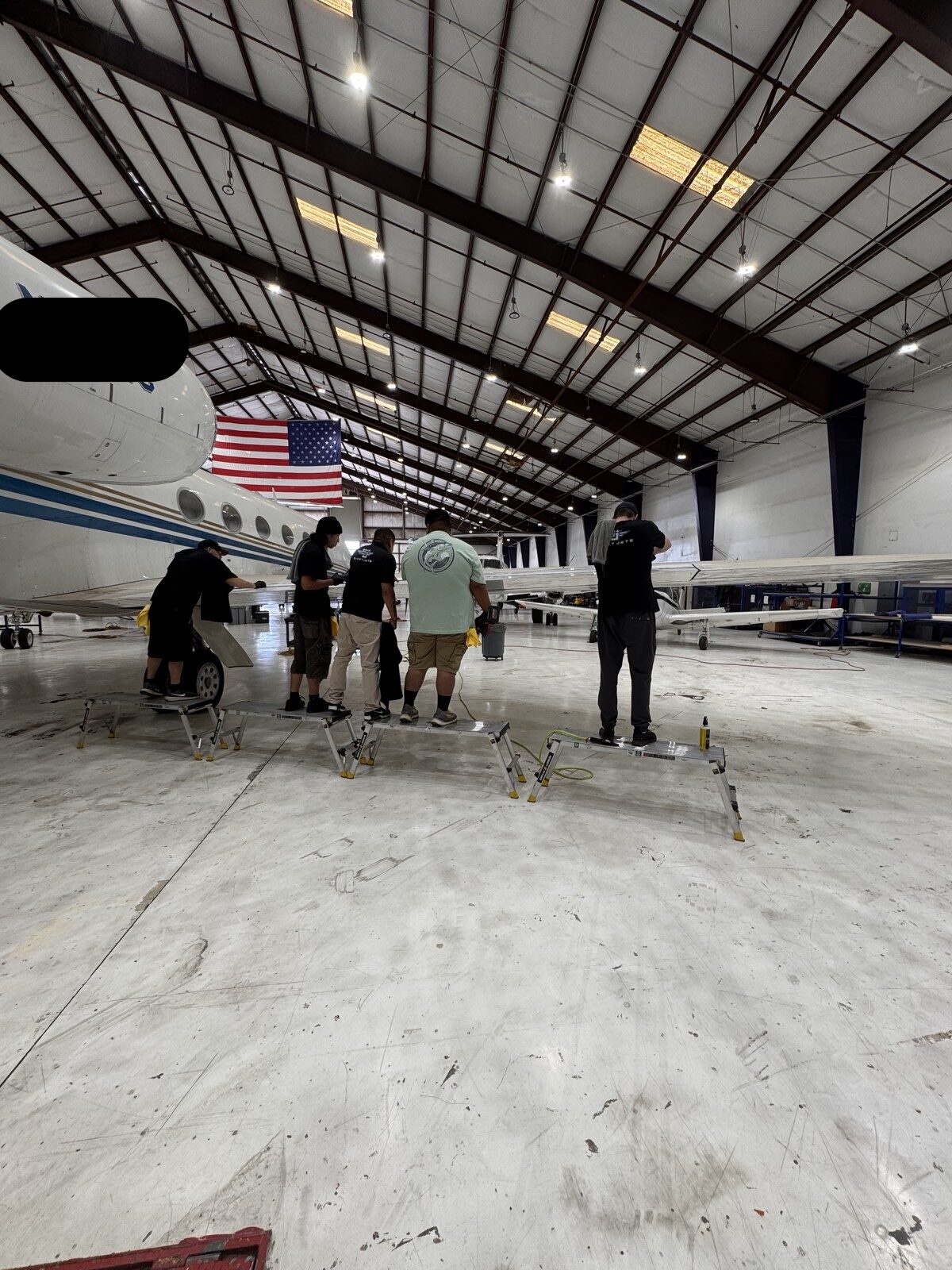 Detailing team working the wing of a business jet from work platforms during a training session