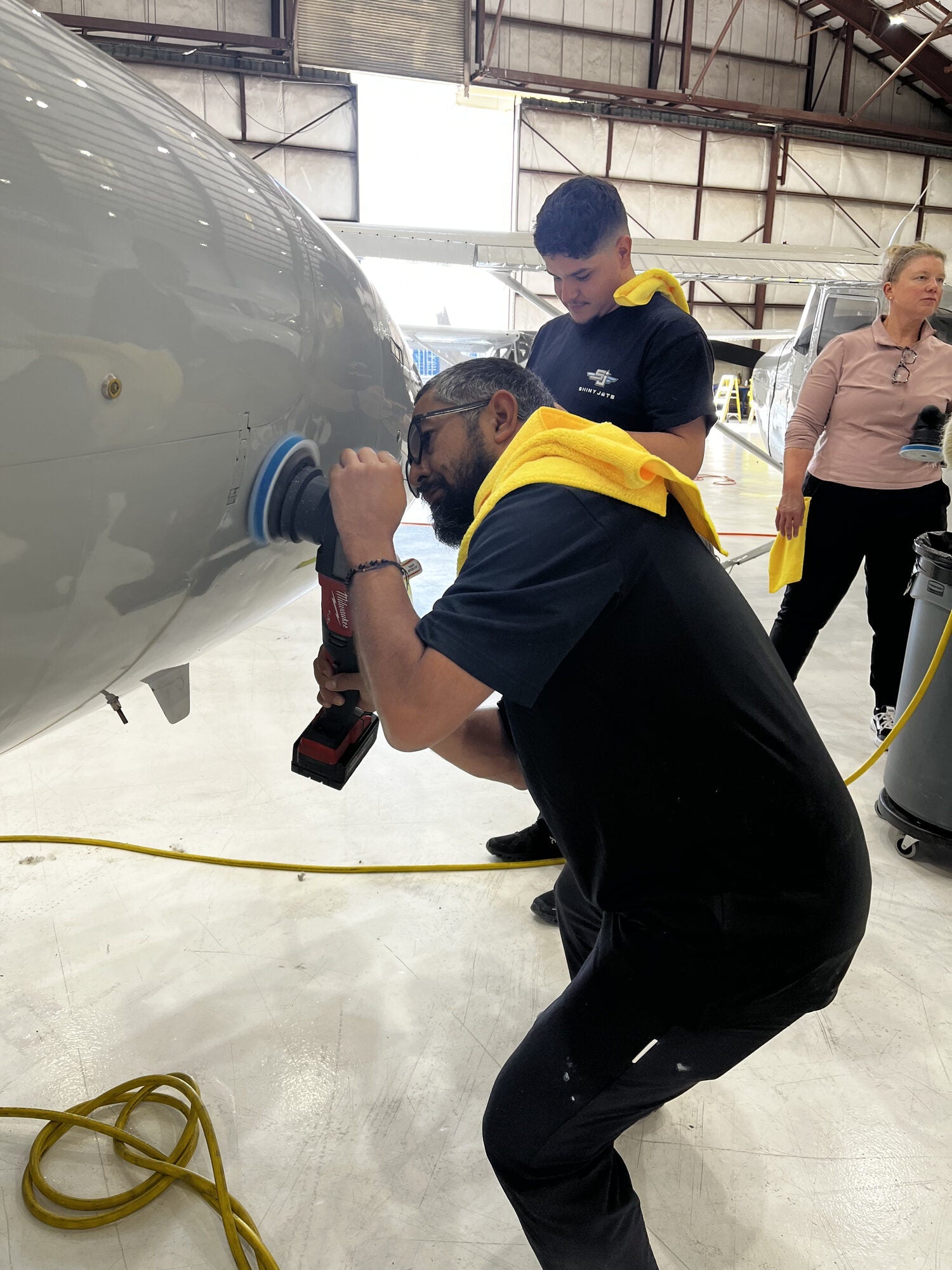 Aircraft detailer polishing the tail of a business jet from a ladder inside the hangar
